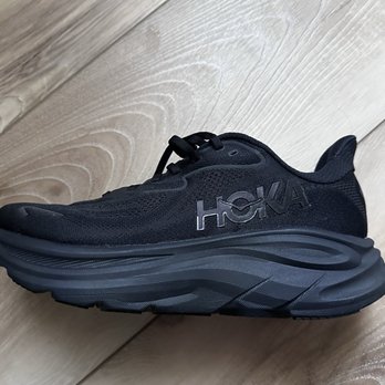DICK'S Sporting Goods - The hubby's shoe from Dicks - A black HOKA running shoe with a thick sole is positioned on a light-colored wooden floor. - Sports Wear Near Me - Cincinnati, Ohio
