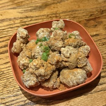 Formosa - Crispy fried chicken bites topped with chopped green onions are served in a small, square, reddish-brown bowl on a wooden table. - Taiwanese Near Me - Brooklyn, New York