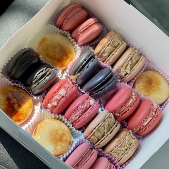 Macaron Delights - an assortment of flavors: creme brûlée, salted caramel, strawberry shortcake, cinnamon toast crunch, and strawberry cheesecake - A box contains colorful macarons in pink, black, beige, and purple, along with mini cupcakes, arranged in paper cups. - Macarons Near Me - Lorton, Virginia
