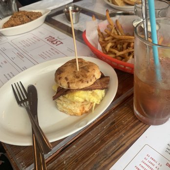 Toast - Breakfast biscuit with crispy bacon and eggs and a side of French fries fried to perfection. - Breakfast & Brunch Near Me - New Orleans, Louisiana Toast - Breakfast biscuit with crispy bacon and eggs and a side of French fries fried to perfection. - Breakfast & Brunch Near Me - New Orleans, Louisiana
