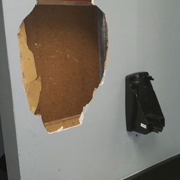 Another hole in the wall with a broken soap dispenser.