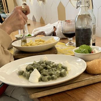 Sfoglia Rina - low key snap of two pasta dishes my neighbor was eating: dandelion gnocchi €13 and tortellini in Parmesan cream €14 - Pasta Shops Near Me - Bologna, BO
