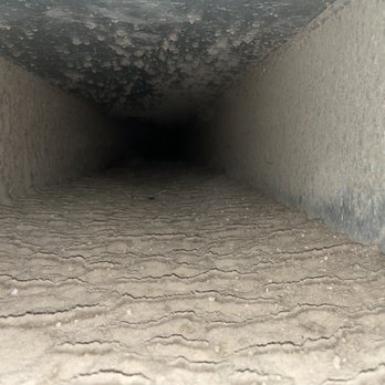 EnviroAir - The return duct before cleaning. - A photograph showing the inside of a narrow duct or pipe with a textured, dusty surface and a dark, unknown end. - Heating & Air Conditioning/HVAC Near Me - Garner, North Carolina