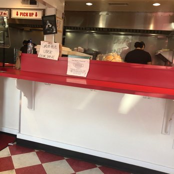 Super Duper Weenie - Inside a restaurant, a counter with a red top and white base is shown, with kitchen staff working behind it and signs indicating pickup and other instructions. - Fast Food Near Me - Fairfield, Connecticut