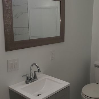 Artdeco home improvement - a bathroom with a sink, toilet and mirror - General Contractors Near Me Artdeco home improvement - a bathroom with a sink, toilet and mirror - General Contractors Near Me