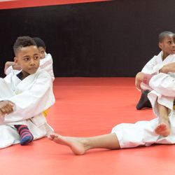 New Vision Academy of Jiu Jitsu - Kids jiu jitsu stretching out.