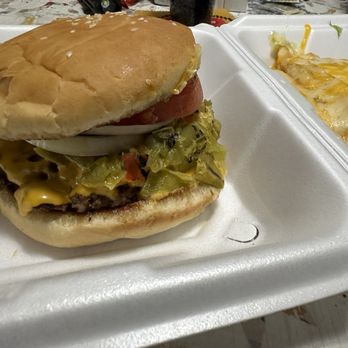 Desert Diamond - 1/2 lb GCCB was delicious - A cheeseburger with lettuce, tomato, onion, and mustard in a bun, served on a foam tray with a side of cheesy enchilada. - American Near Me - Socorro, New Mexico
