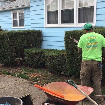 Flores Landscaping - a man with a wheelbarrow in front of a house - Landscaping Near Me