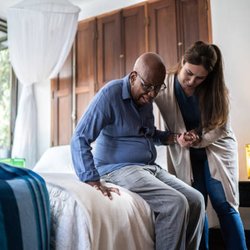 Porter Home Health Services - Helping a client get out of bed in his home after helping him get dressed