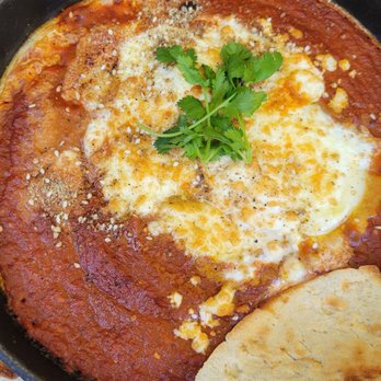 Empire Cafe - SHAKSHOUKA Moroccan baked eggs baked in a spicy tomato stew with feta, dukkah and cilantro served with pita chips - Breakfast & Brunch Near Me - Houston, Texas