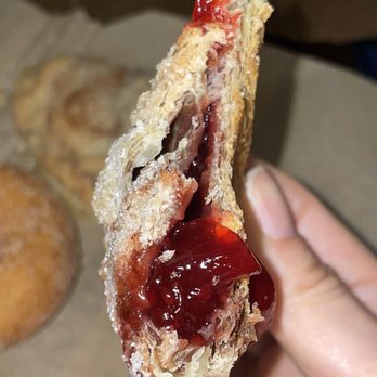 Yates Cider Mill - a hand holding a half eaten pastry - Donuts Near Me - Orion Township, Michigan