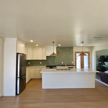 Cordada Construction Inc - This remodeled kitchen blends warmth and simplicity with custom white cabinetry, a large center island, green tile backsplash, brass fixture - General Contractors Near Me Cordada Construction Inc - This remodeled kitchen blends warmth and simplicity with custom white cabinetry, a large center island, green tile backsplash, brass fixture - General Contractors Near Me