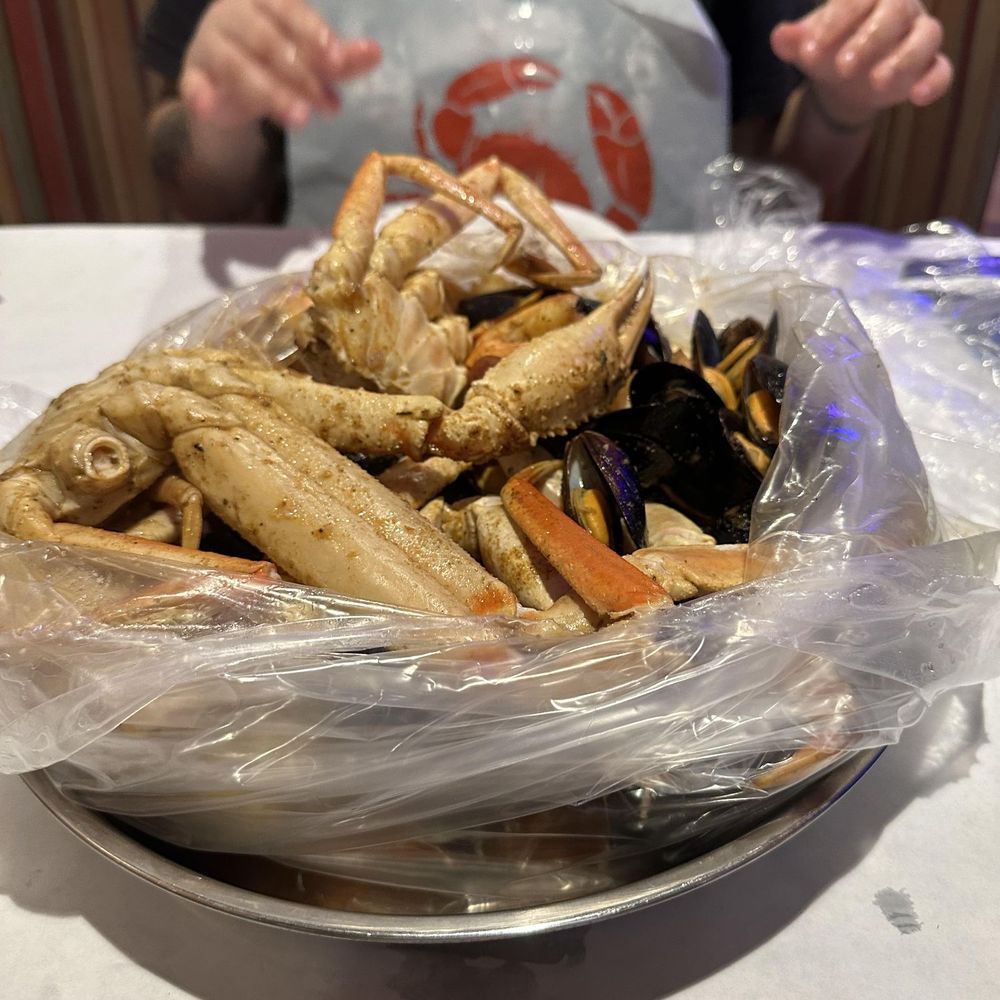 King Crab - a woman sitting at a table with a plate of food - Seafood Near Me - Rochester, New York King Crab - a woman sitting at a table with a plate of food - Seafood Near Me - Rochester, New York