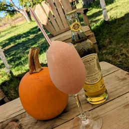 Glass of frozé with a bottle of spiced apple cider