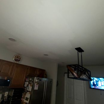Ironshore Construction - Kitchen ceiling - paint does not match as guaranteed; posted as part of 1 star review by Bree A. - A kitchen ceiling shows mismatched paint, with a modern black metal light fixture hanging, and a TV visible on the wall. - Painters Near Me
