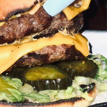 Per Diem - Tour Burger* - A burger with lettuce, pickles, melted cheese, and beef patties stacked inside a bun, with some char marks visible. - American Near Me - Lititz, Pennsylvania