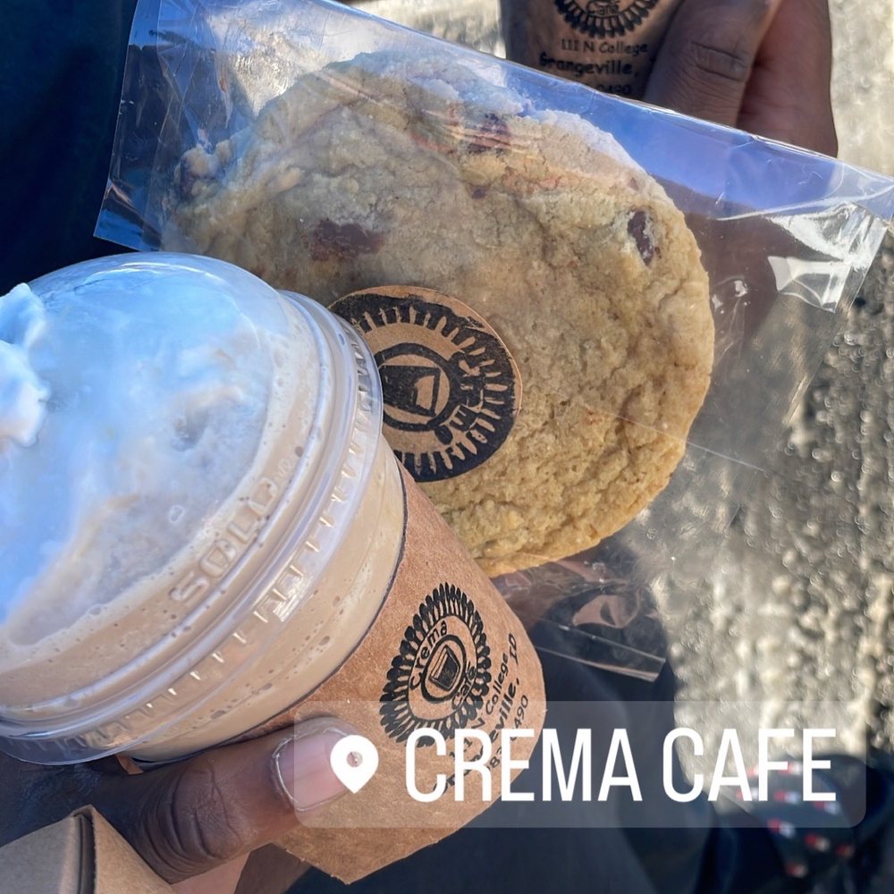 a person holding a cookie and a cup of coffee