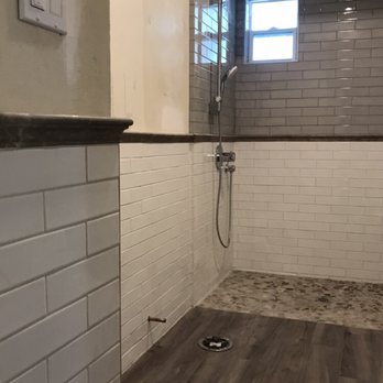 Select Tile & Stone - 2x8 porcelain tile white/gray subway pattern, limestone chair rail,no curb shower with wood looking floor,river rock shower pan - General Contractors Near Me