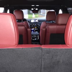 Jasmyne Enterprises - The interior of a car is shown, focusing on the rear seats and dashboard. The seats are upholstered in a rich, deep red leath...