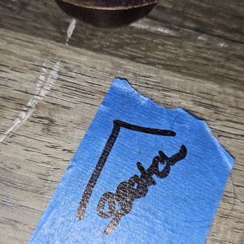 Express Flooring - A torn piece of blue paper with the word "good" handwritten in black ink, placed on a wooden surface. - Flooring Near Me - Rio Rancho, New Mexico