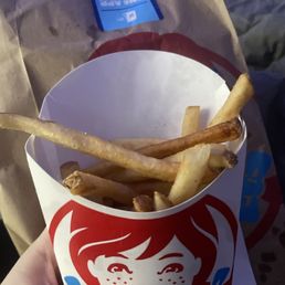 a hand holding a cup of fries a hand holding a cup of fries