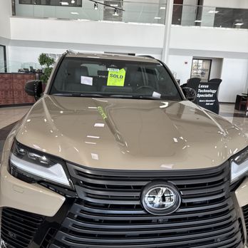 Arrowhead Lexus - A beige Lexus SUV is shown inside a dealership showroom, with a 'sold' sign on the windshield and the dealership's interior visible in the background. - Car Dealers Near Me - Peoria, Arizona