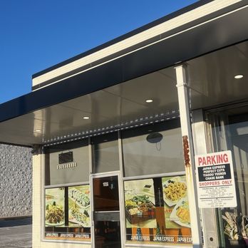 Japan Express - Outside - The image shows the storefront of Japan Express, a casual Japanese eatery, with a parking sign and large window displays under a clear blue sky. - Japanese Near Me - Plainview, New York