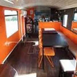 Le Bus Thaï - L'interieur avec les tables et la cuisine au fond