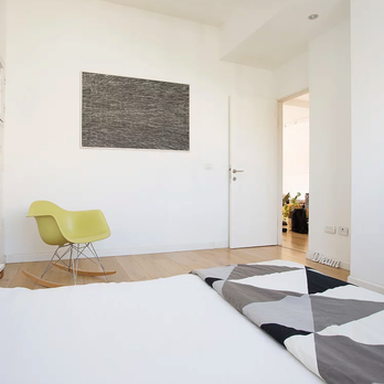 Alpha Constructions & Renovations - a white bedroom with a yellow chair - General Contractors Near Me