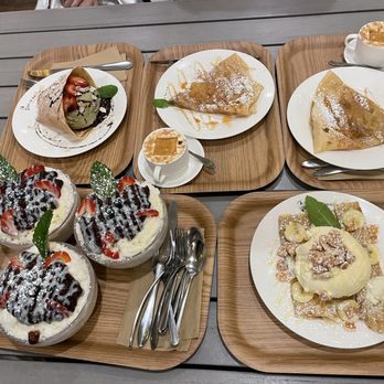 Cafe Bench - Red Bean Shaved Ice, It is I, The Pancake Crepe, Lady Nana Crepe, Affogato Coffee, Sweet Forest Crepe - A cafe table displays various desserts including crepes, ice cream sundaes, and coffee drinks on wooden trays. - Cafes Near Me - Flushing, New York
