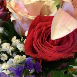 Condition of flowers upon arrival and in their option nothing wrong with brown edges! - A floral arrangement includes a red rose, white lilies, and small white and purple flowers, with green foliage.