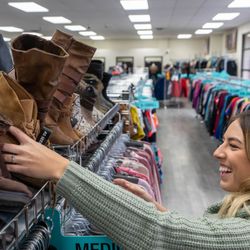 Blond girl in mint sweater looking at boots.