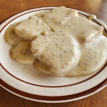 Bea's Mexican Restaurant 2 - Biscuits and peppery gravy. - Biscuits smothered in a creamy, peppery gravy are presented on a white plate, likely at a restaurant or diner. - Mexican Near Me - Albuquerque, New Mexico