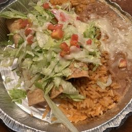 Taquitos - A foil container holds Mexican food with rice, shredded lettuce, diced tomatoes, cheese, and a burrito.