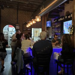 PizzaVino NoCo Italiano - Bar interior with diners and TVs: Packed bar area, hockey on the screens