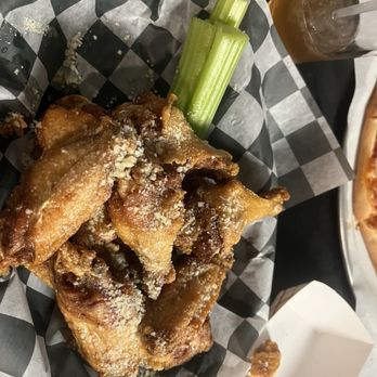 3rd Base Bar & Grill - Butter Garlic Parmesan wings - Crispy fried chicken wings sprinkled with seasoning, served with celery sticks and a beverage in a restaurant setting. - Sports Bars Near Me - Olean, New York
