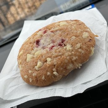 The Human Bean - Raspberry cream cheese muffin top - A muffin with raspberry and cream cheese visible on top, resting on white paper on a surface. - Coffee & Tea Near Me - Los Lunas, New Mexico