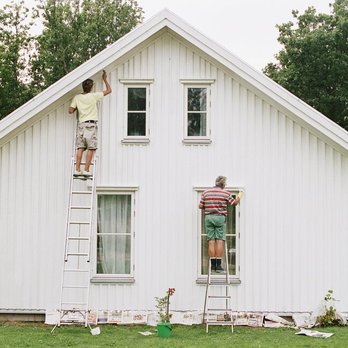 Four Seasons - a man on a ladder painting a house - Flooring Near Me