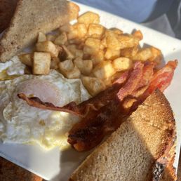 Two eggs over easy, delicious toast, home fries, bacon