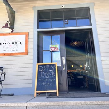A Daily Dose - The image shows the front entrance of Daily Dose Café + Lounge, featuring a glass door with an 'We're Open' sign and a chalkboard menu outside. - Juice Bars & Smoothies Near Me - Crested Butte, Colorado