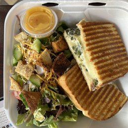 a sandwich and salad in a styrofoam container