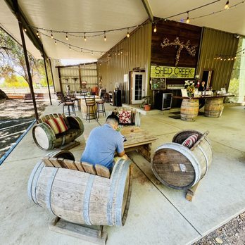 Shed Creek Cellar - a man sitting at a table with wine barrels - Wineries Near Me - Napa, California Shed Creek Cellar - a man sitting at a table with wine barrels - Wineries Near Me - Napa, California