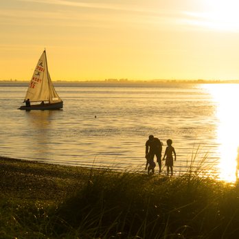Blackie Spit Park - "Upsy, Daddy" as man and two children walk on the beach and sailboat goes by - Beaches Near Me - Surrey, British Columbia Blackie Spit Park - "Upsy, Daddy" as man and two children walk on the beach and sailboat goes by - Beaches Near Me - Surrey, British Columbia