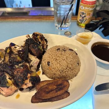 Aldeez Afribbean Restaurant - Plate: Jerk Chicken 2 Sides: Rice & Peas / Plantains With a cold Champagne Kola to drink Extras: Pepper Sauce & Jerk Sauce - Caribbean Near Me - Dallas, Texas