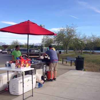 Denali Sausage - two men standing at a table with a red umbrella - Food Stands Near Me - Anchorage, Alaska