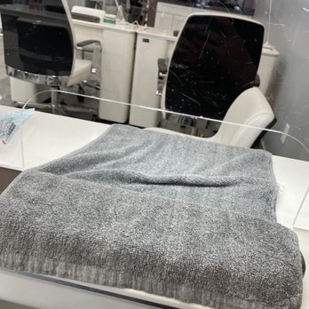 Joy Spa & Nails - Nail area - A gray towel is folded on a white table, with a clear plastic barrier in front, in a setting that appears to be a nail salon or spa. - Nail Salons Near Me - Albuquerque, New Mexico
