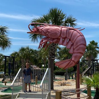 Shrimpy's Grill and Golf - a man standing in front of a giant shrimp - Mini Golf Near Me - Gulf Shores, Alabama Shrimpy's Grill and Golf - a man standing in front of a giant shrimp - Mini Golf Near Me - Gulf Shores, Alabama