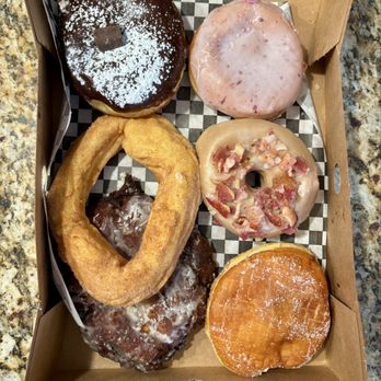 The Goods - Bottom left clockwise: apple fritter, cruller, chocolate eclair thingy , berry, maple bacon and the one filled with a Nutella foam/creme. - Donuts Near Me - Carlsbad, California