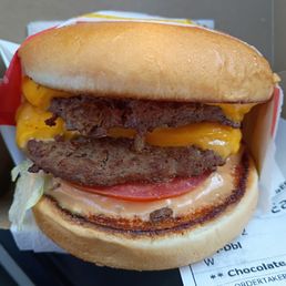 A burger with barely one skinny piece of lettuce A burger with barely one skinny piece of lettuce