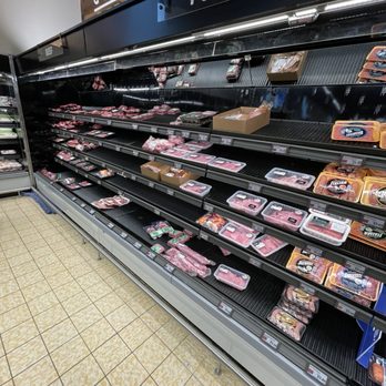 ALDI - a display of meat in a grocery store - The image shows an aisle in a grocery store with a sign indicating the meat section, specifically for pork. The shelves are mostly empty, with only a few packages of meat remaining. The floor is tiled, and the store appears clean and organized. - Grocery Near Me - Rumford, Rhode Island